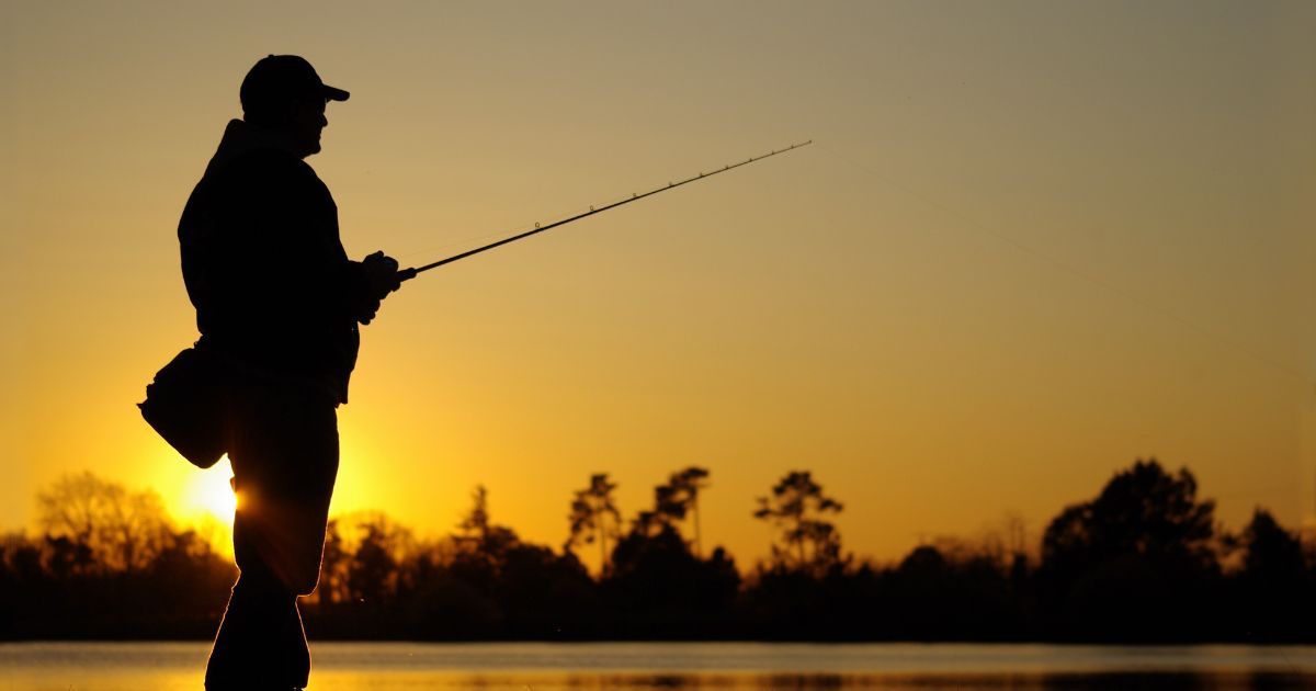 silhouette of man fishing at sunset