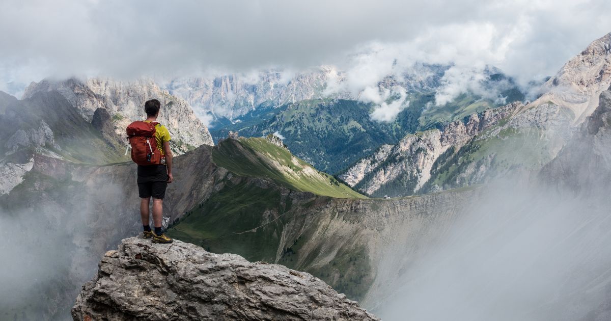 man standing on rock overlooking mountains
