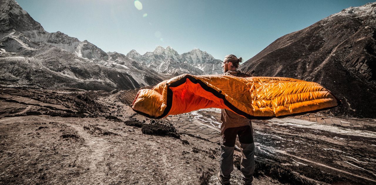 man shaking out his sleeping bag