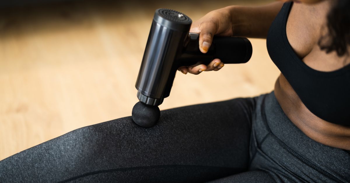woman using massage gun on quad