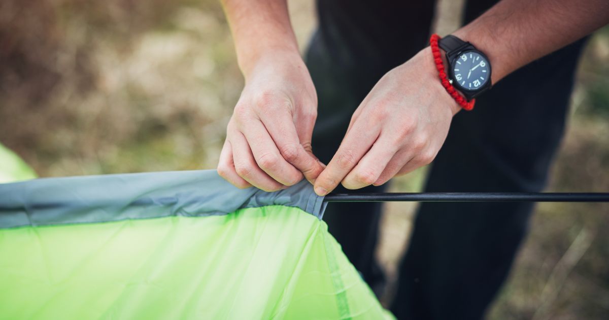 man threading tent poles through tent