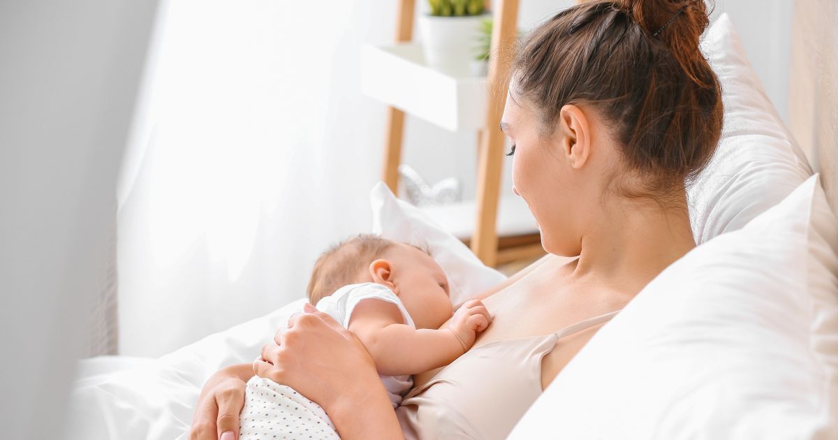 mother breast feeding child in bed