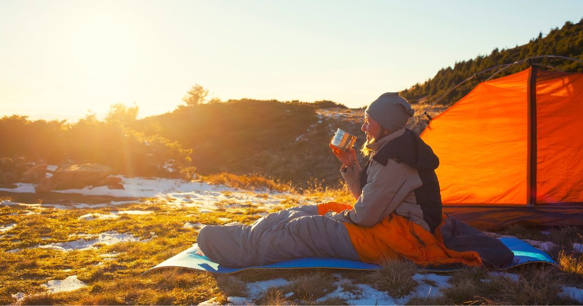 girl sitting in sleeping bag drinking from a cup