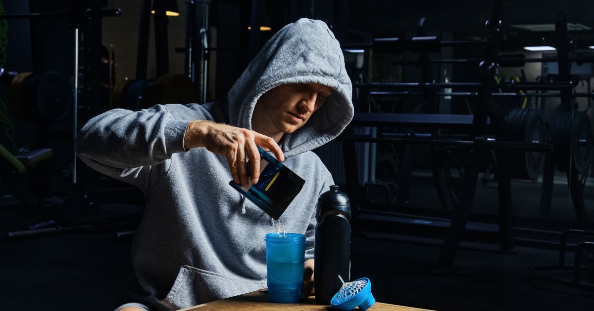 man pouring powdered supplement into cup