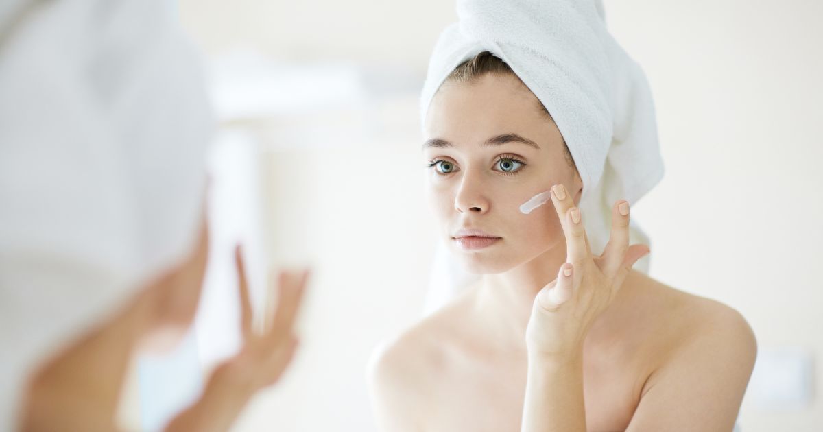 woman applying cream to face