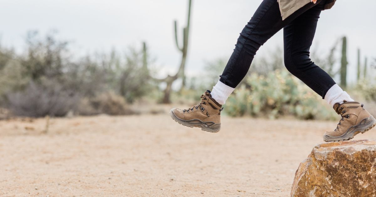 person with hiking boots stepping off rock