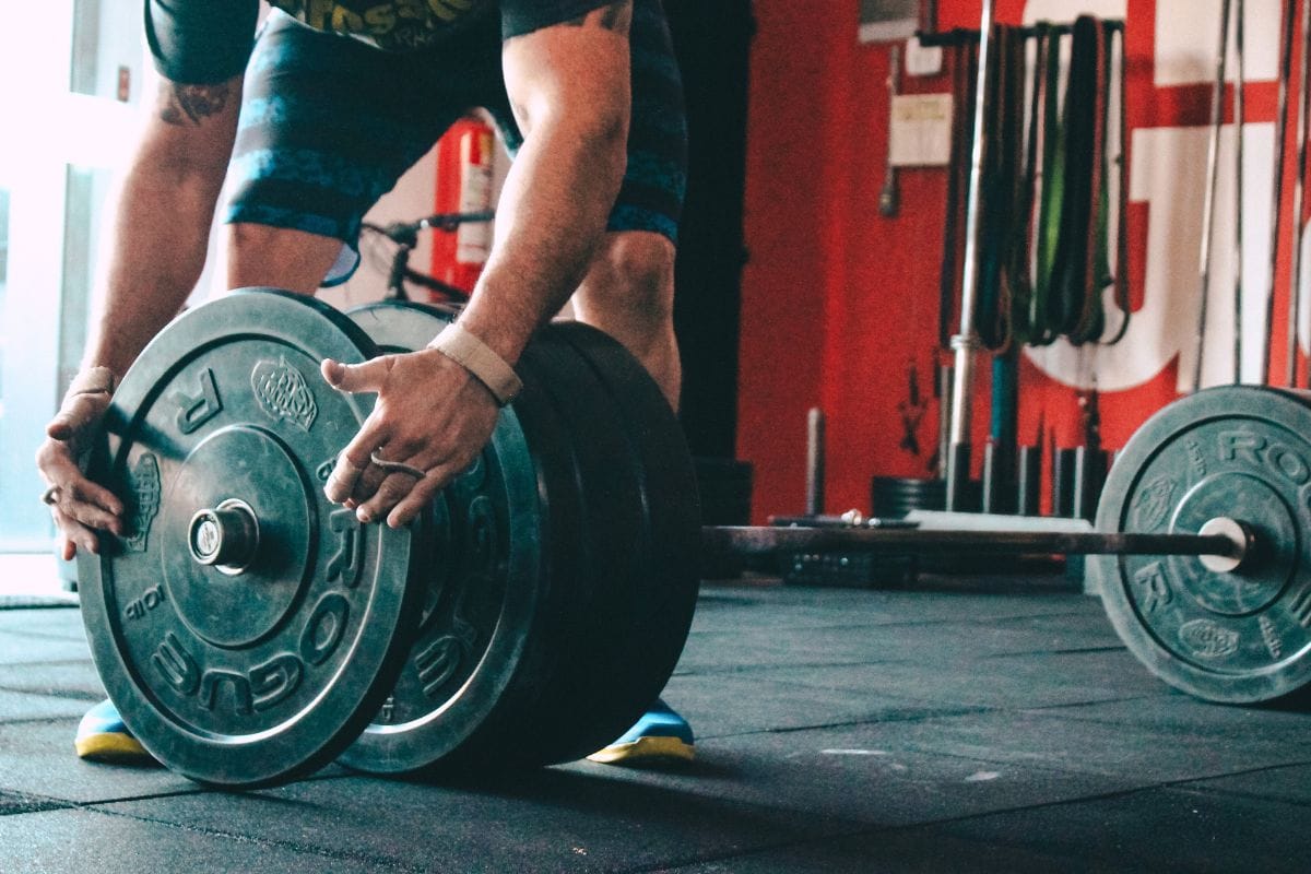 man putting weights on barbell